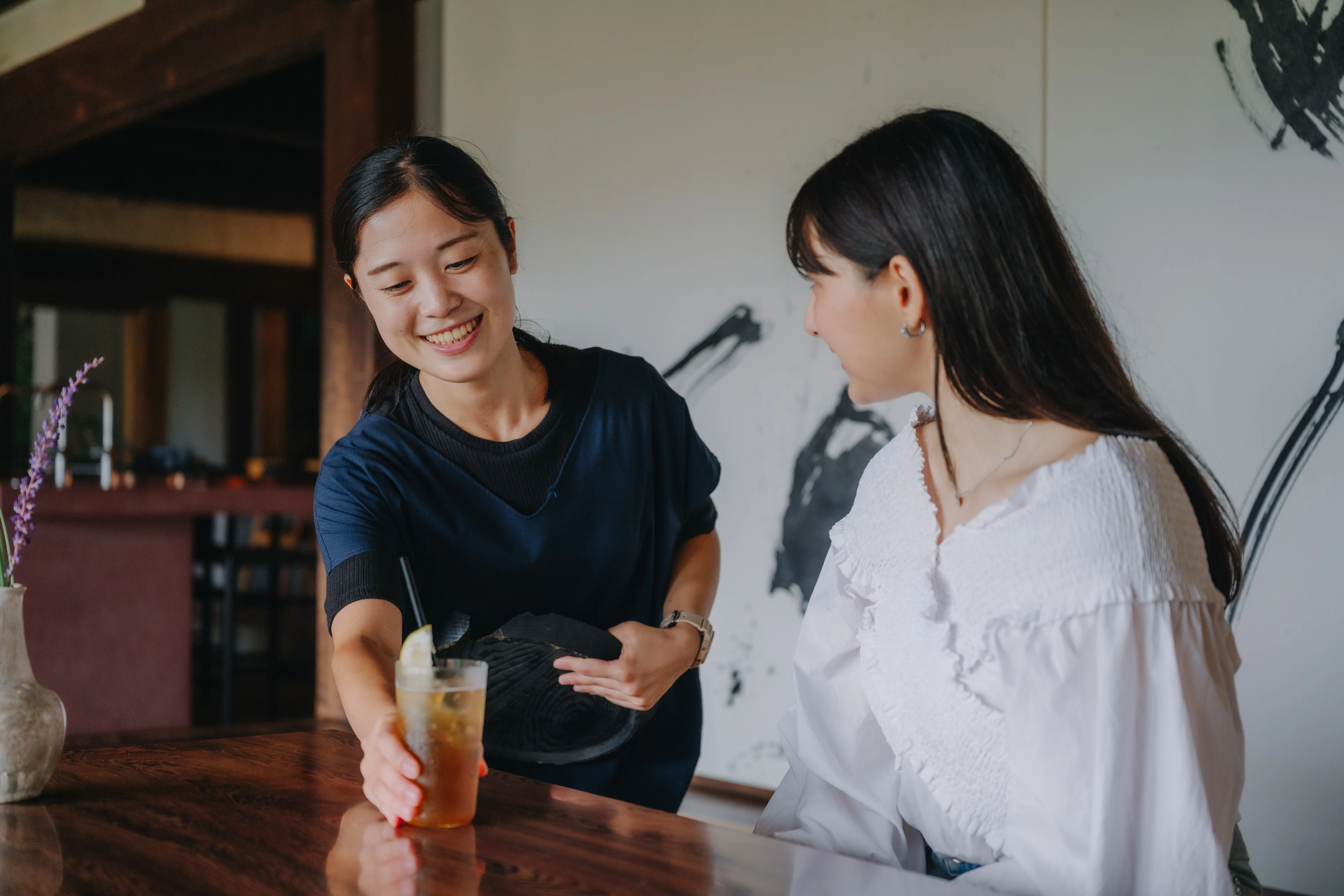 カウンター越しに飲みものを受け取る二人