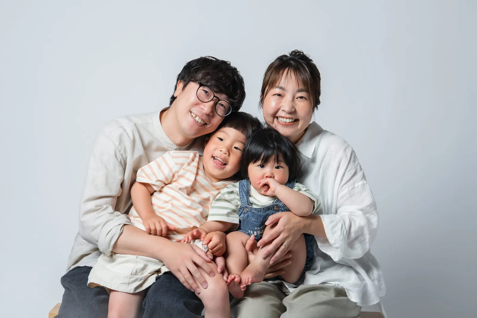 子どもを囲んで笑う家族の記念写真