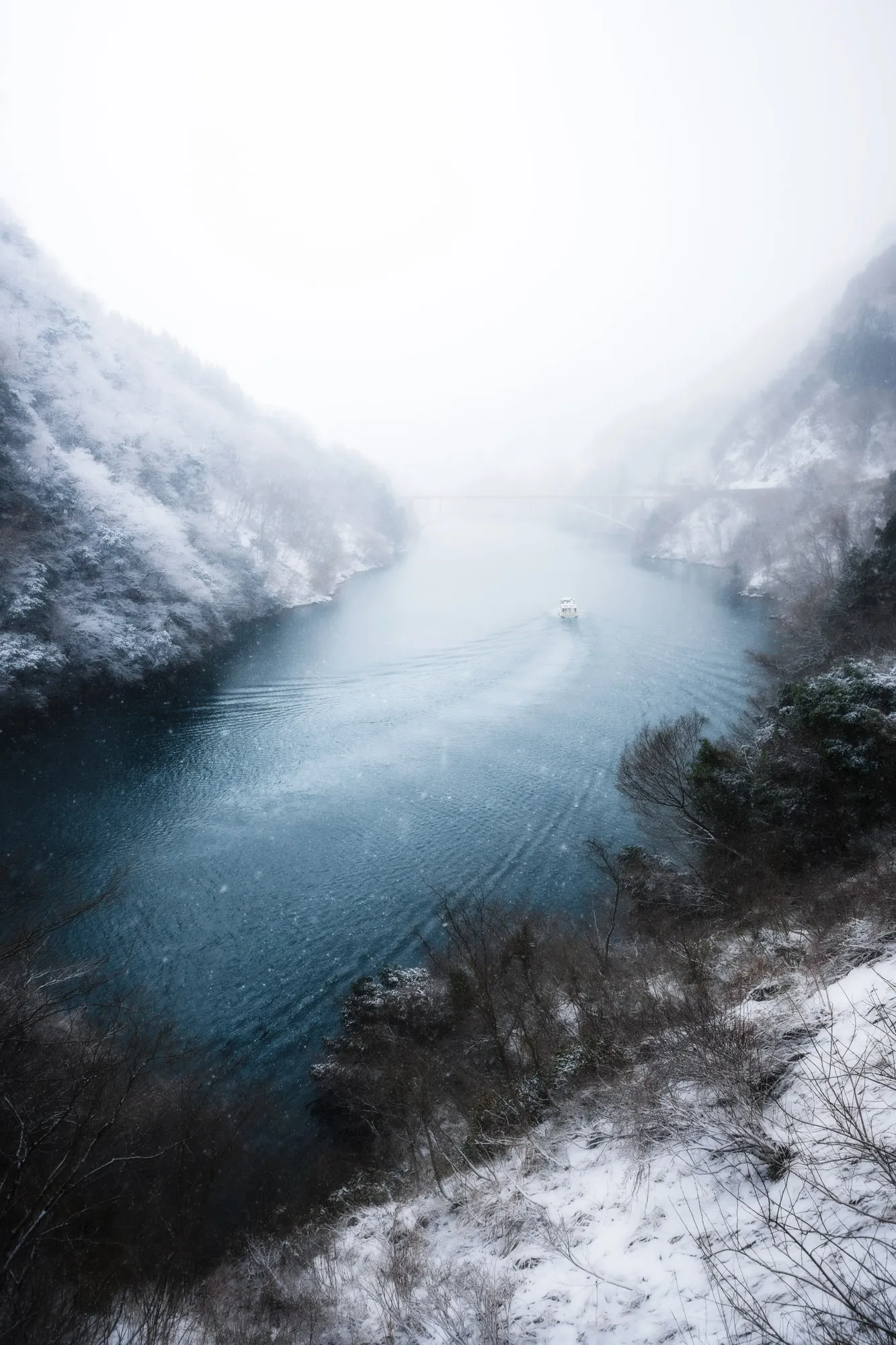 雪に包まれた峡谷を舟が渡る